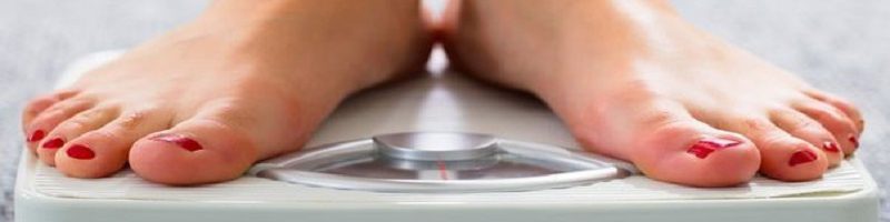 پاهای یک خانم روی یک ترازوی سفید رنگ